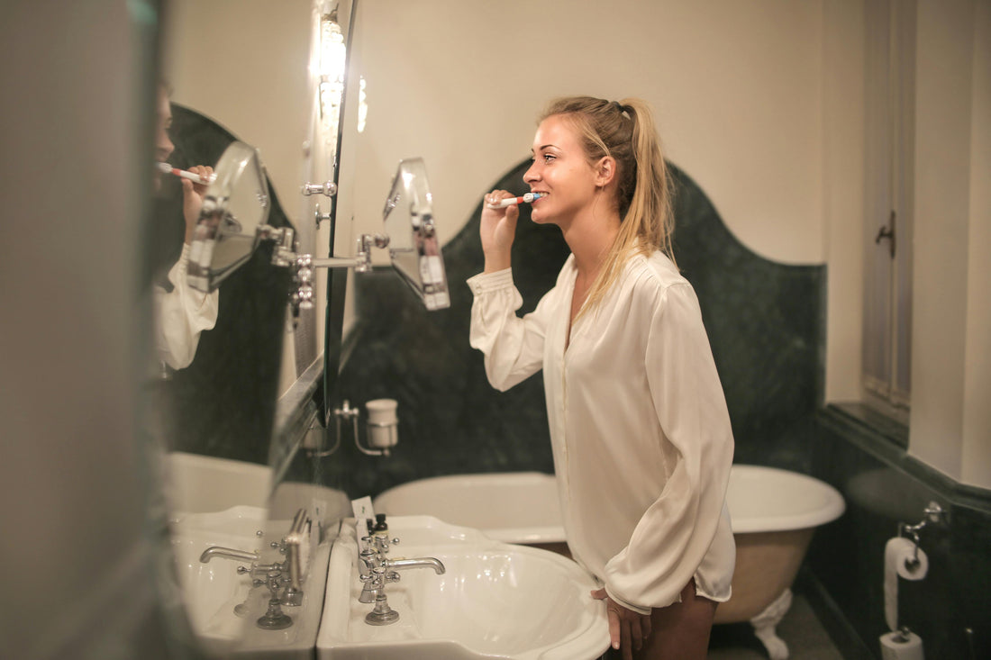 A woman brushes her teeth whilst listening to "The Gift of Self-care" Podcast