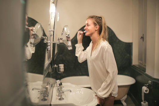 A woman brushes her teeth whilst listening to "The Gift of Self-care" Podcast